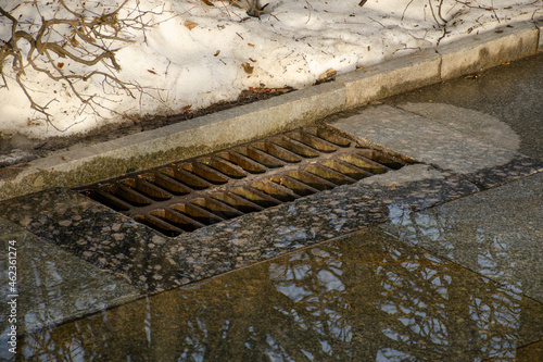 Melt water is poured into the storm sewer. Street storm sewer during snow melting.