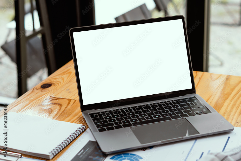 Side view of contemporary workplace with laptop computer, notebook, coffee cup and stationery on wooden table. clipping path. Side view of contemporary workplace with laptop computer, notebook, coffee cup and stationery on wooden table. clipping path.