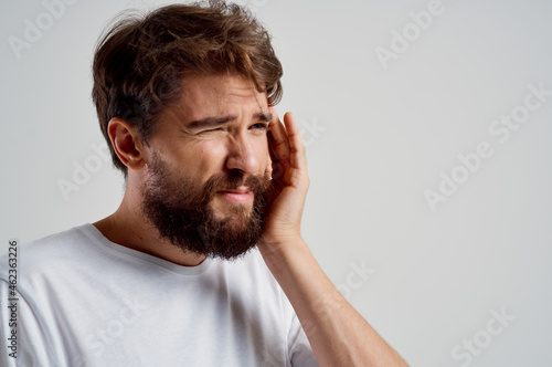 emotional man in a white t-shirt headache migraine problems isolated background © SHOTPRIME STUDIO