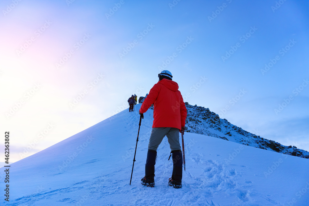 Mountaineer reaches the top of a snowy mountain in a sunny winter day Mountaineer reaches the top of a snowy mountain in a sunny winter day