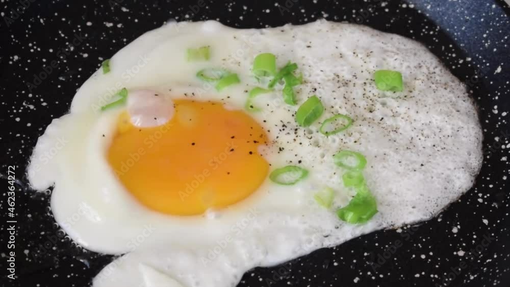 Frying chicken egg with ground pepper and scallion on the skillet. Cooking breakfast. Zoom out Frying chicken egg with ground pepper and scallion on the skillet. Cooking breakfast. Zoom out