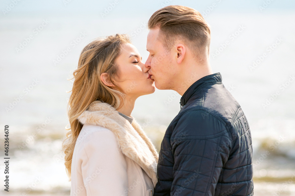 Young couple kissing outdoor.Stunning outdoors portrait of young stylish fashion couple posing in autumn sea background. Young couple kissing outdoor.Stunning outdoors portrait of young stylish fashion couple posing in autumn sea background.