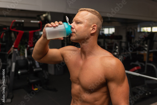 Young caucasian man drinking water after exercise.man in the gym drinking from the shaker.
