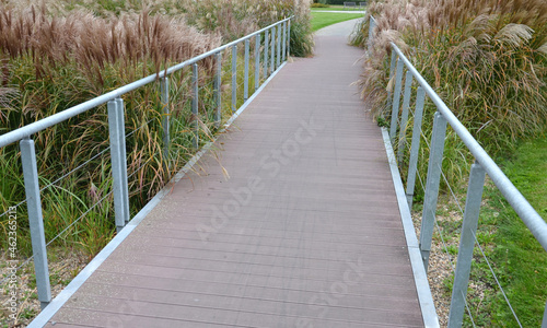 wooden bridge with metal galvanized structure in the park. newly built for cyclists across the stream by the pond. wooden beams connected with screws and rope stainless steel cable railings photo