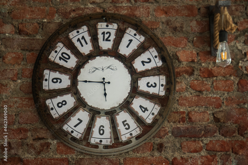 a clock and lamp hanging on a red brick wall. Selective Focus Clock