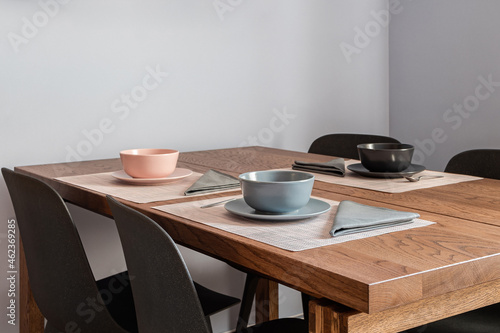 Stylish dining room interior with a wooden table set for three people with bowls and cutlery © Pavel