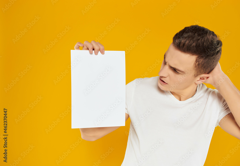 man in white t-shirt blank sheet of paper presentation yellow background man in white t-shirt blank sheet of paper presentation yellow background
