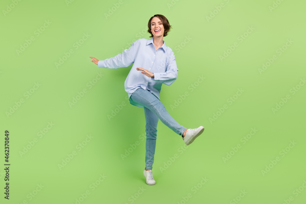 Full length photo of young woman happy positive smile have fun dance isolated over green color background Full length photo of young woman happy positive smile have fun dance isolated over green color background