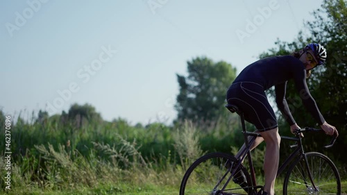 Cyclist in helmet starting his ride by the empty road along the countryside