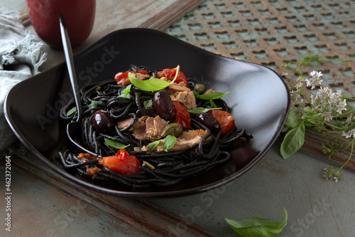 plate with black putanesca spaghetti on a wooden table photo