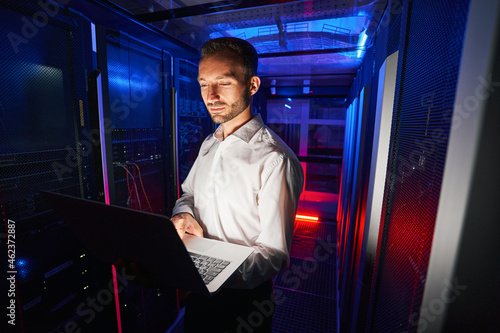 System technician running diagnostic of server racks with laptop photo