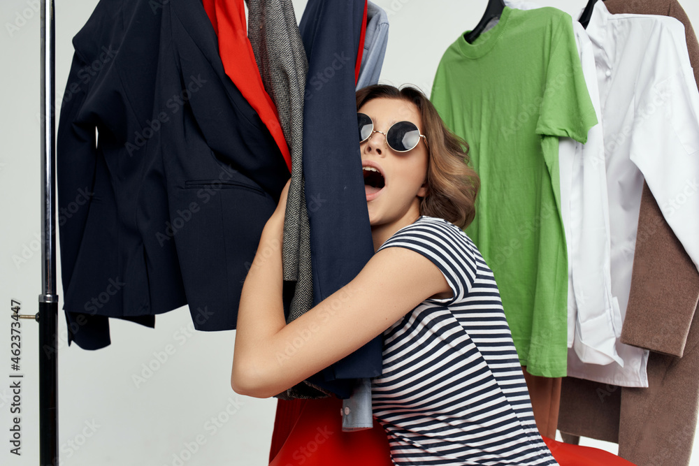 beautiful woman with glasses next to clothes fashion fun isolated background