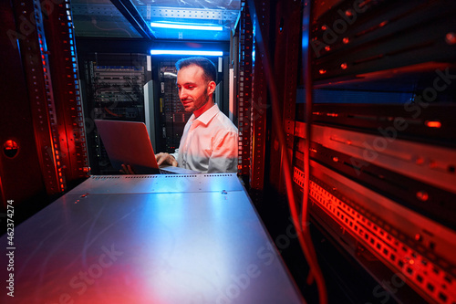 Data center system administrator checking server settings with laptop Fototapet