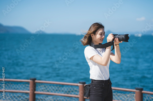 海辺で写真を撮るカメラ女子