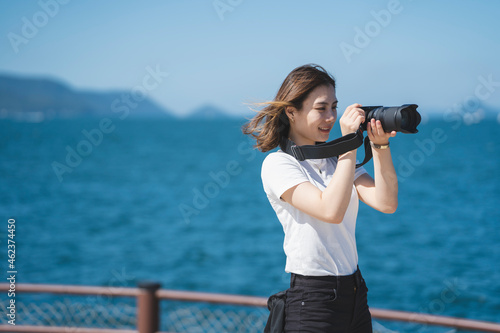 海辺で写真を撮るカメラ女子