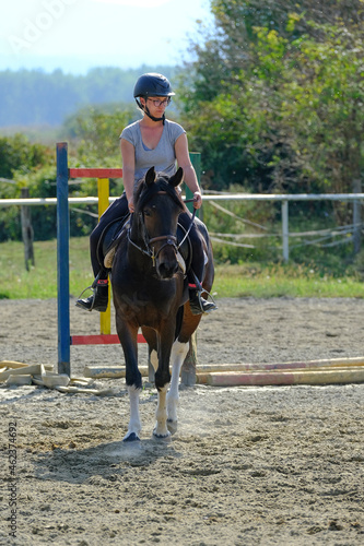 Girl rides a pony horse in riding school