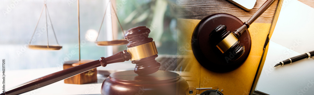Justice and law concept.Male judge in a courtroom with the gavel, working with, computer and docking keyboard, eyeglasses, on table in morning light Justice and law concept.Male judge in a courtroom with the gavel, working with, computer and docking keyboard, eyeglasses, on table in morning light
