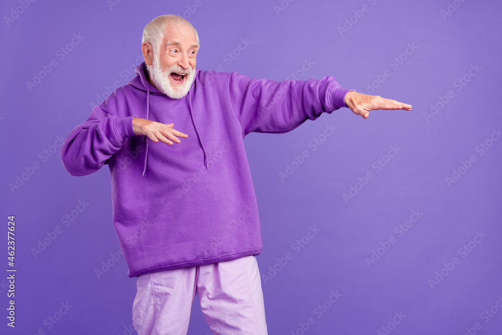 Portrait of attractive cheerful grey-haired man having fun moving clubbing dancing isolated over bright violet purple color background Portrait of attractive cheerful grey-haired man having fun moving clubbing dancing isolated over bright violet purple color background