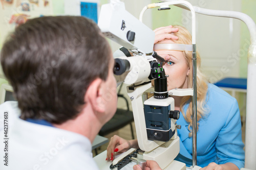 Fototapeta Naklejka Na Ścianę i Meble -  The patient passes an ophthalmologic examination, the doctor checks the health of the eyes and visual acuity. The laser beam shines into the patient's eye. Ophthalmologist conducts vision diagnostics.