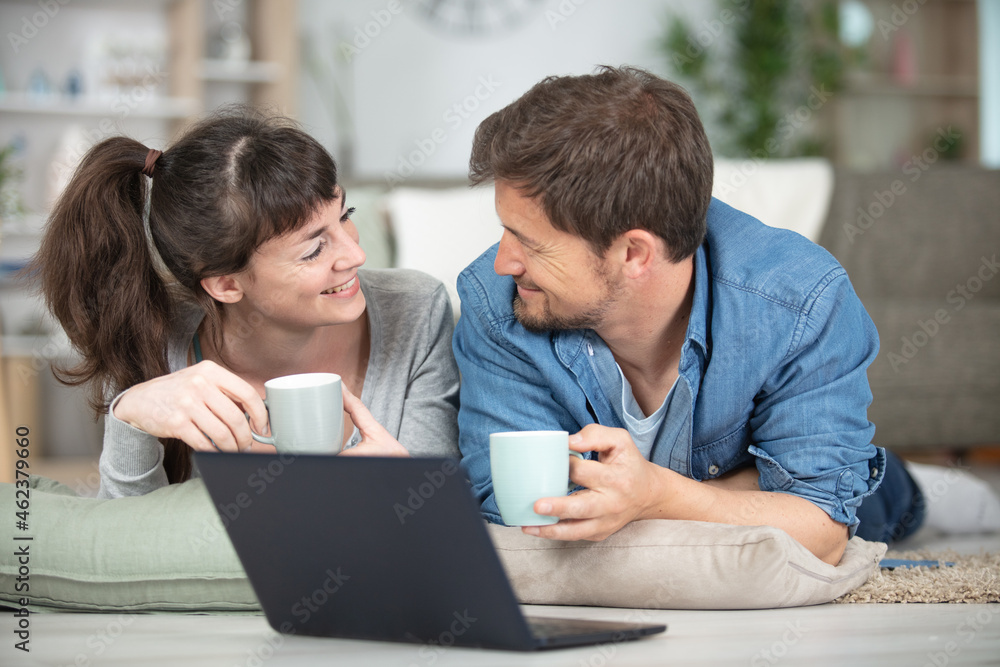 smiling couple typing on laptop at home smiling couple typing on laptop at home