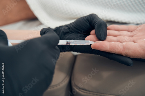 Doctor cosmetologist making injection into male finger