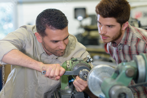 engineer exerting effort to turn component on machine photo