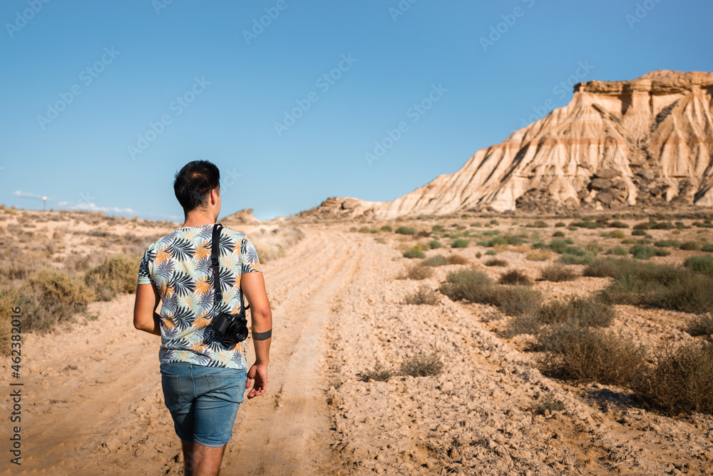 Young man with a camera in Bardenas Reales desert, Navarra, Basque Country.
