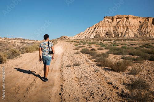 Young man with a camera in Bardenas Reales desert, Navarra, Basque Country.