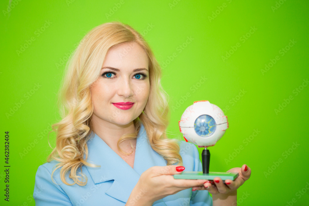 The girl doctor ophthalmologist is holding demonstrative false eyes in her hands. A beautiful girl undergoes an ophthalmological examination, checks her eye health and visual acuity. The girl doctor ophthalmologist is holding demonstrative false eyes in her hands. A beautiful girl undergoes an ophthalmological examination, checks her eye health and visual acuity.
