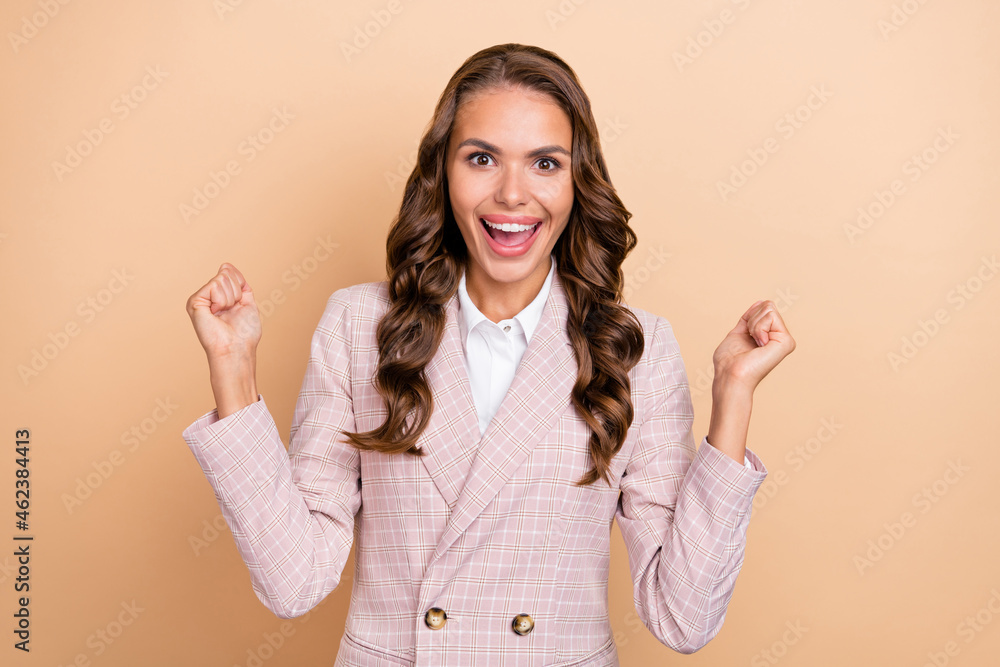 Portrait of delighted positive lady raise fists shout yes hooray look camera isolated on beige color background Portrait of delighted positive lady raise fists shout yes hooray look camera isolated on beige color background
