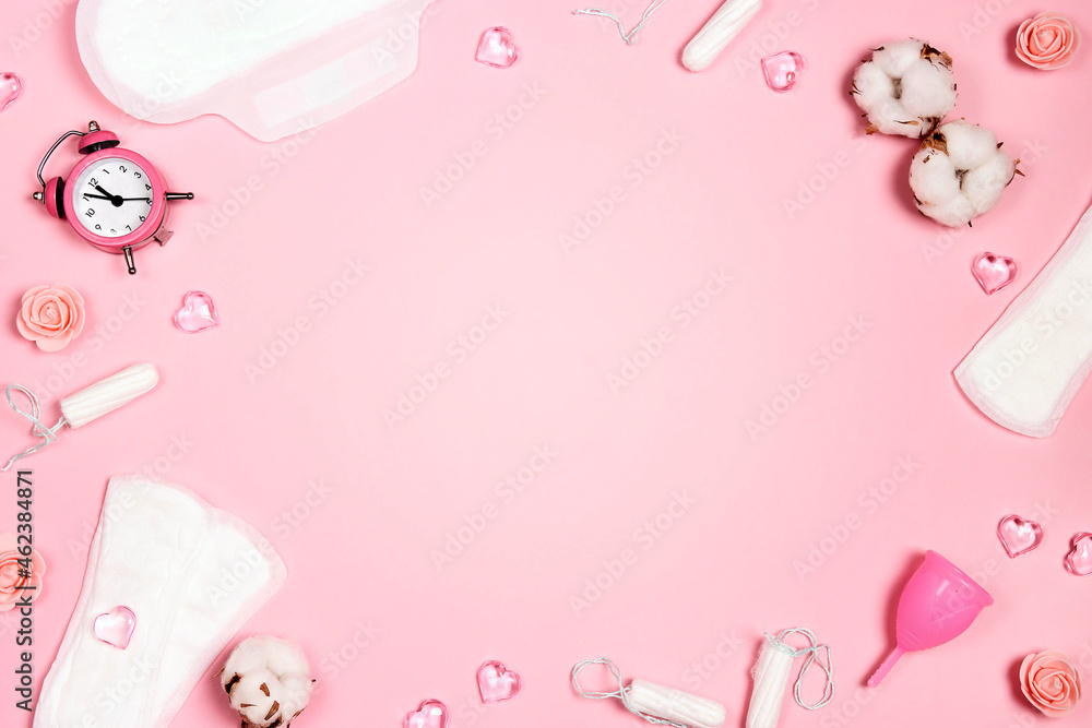 Frame from women's sanitary napkins, tampons, menstrual cup, hearts and flowers on pink background. Copy space for text. Frame from women's sanitary napkins, tampons, menstrual cup, hearts and flowers on pink background. Copy space for text.