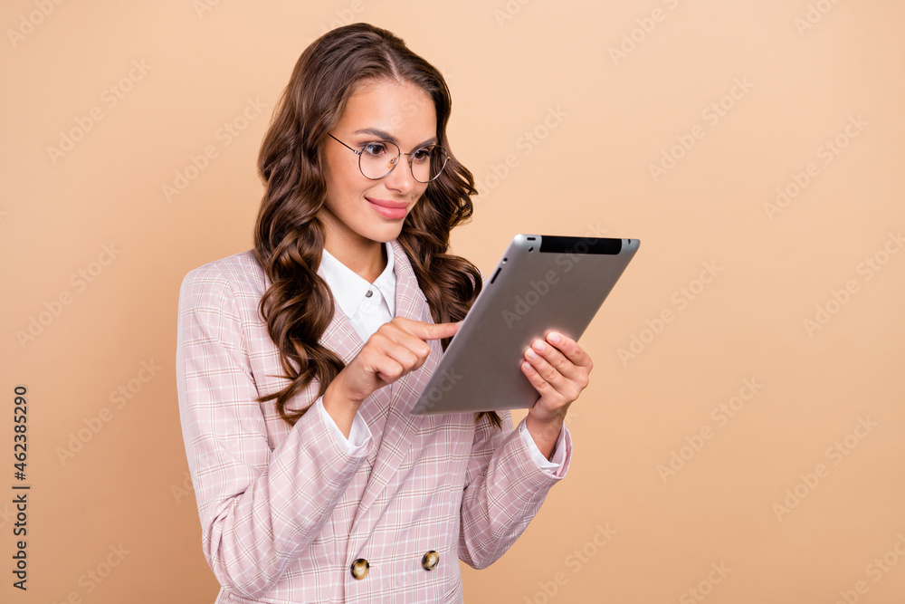 Photo of satisfied pretty lady hold use tablet have good mood coworking networking isolated on beige color background Photo of satisfied pretty lady hold use tablet have good mood coworking networking isolated on beige color background