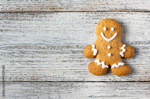 One Christmas gingerbreads man with patterns of glaze on a white wooden background.