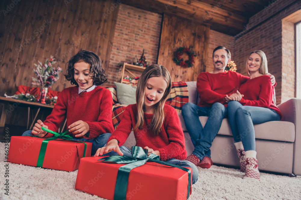 Full size photo of excited little kid open gift box mom an dad sit couch admire enjoy holiday together indoors