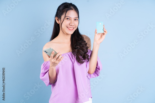 Young Asian girl using smartphone on blue background
