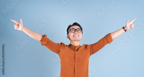 Young Asian businessman posing on blue background
