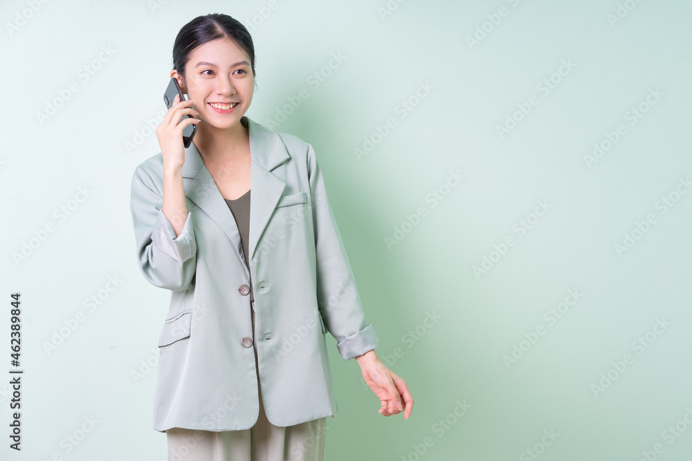Young Asian businesswoman holding smartphone on green background Young Asian businesswoman holding smartphone on green background