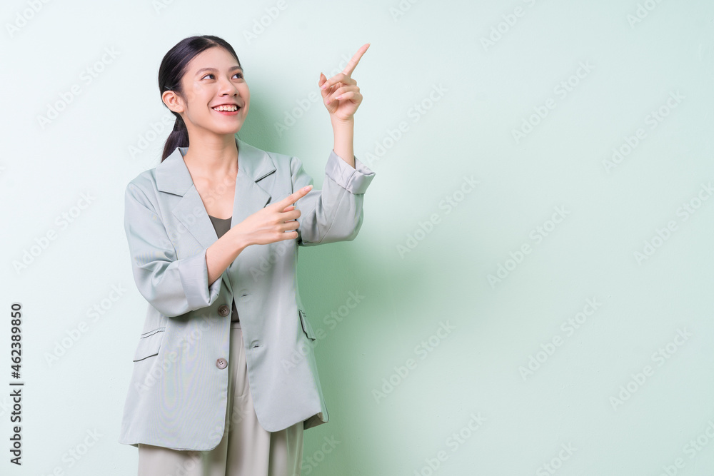 Young Asian businesswoman wearing green suit on green background Young Asian businesswoman wearing green suit on green background