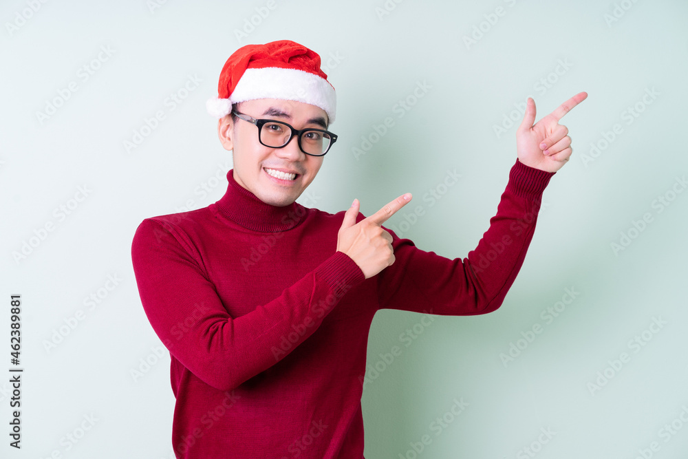 Young Asian man wearing christmas hat on green background Young Asian man wearing christmas hat on green background