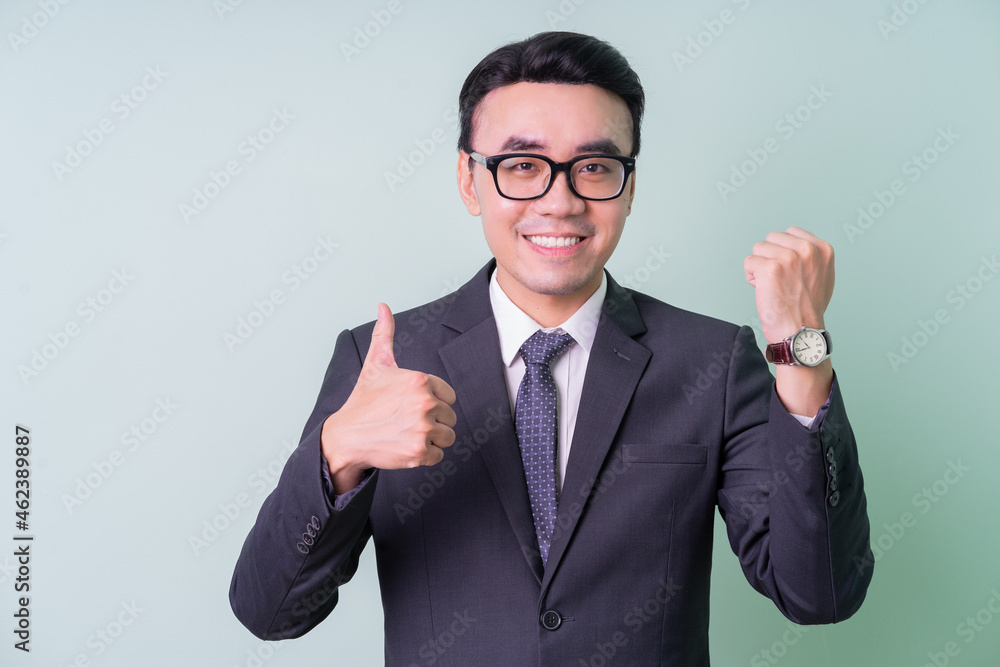 Young Asian businessman posing on green background