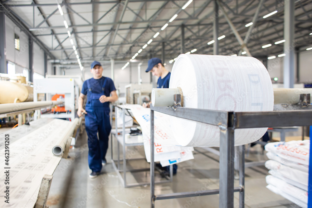 Fototapeta premium Workers in a factory carry out technological processes on a conveyor line in protective overalls