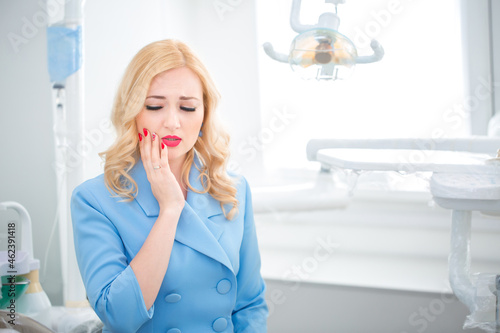 Dental clinic. The girl sits in the dental chair at the reception at the dentist complains of toothache. Dentistry and orthodontist. Dental treatment and bite correction. Emotion of pain and pity.