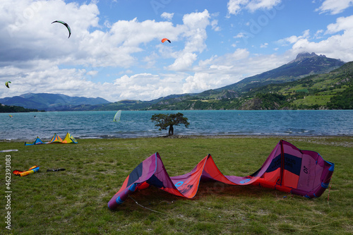 kitesurfers on lake and colorful sails on beach in serre ponçon alps france