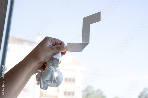 Fotografia Close up of a Woman hand removing a vinyl sticker from a window with a tool