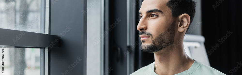 Obraz premium Arabian businessman looking at window in office, banner