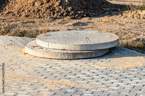 Bottoms of reinforced concrete pit and sewer lie outdoors. Reinforced concrete products on construction site. Industrial production facilities for sewer wells.