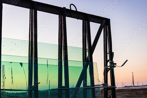 New sealed glass units at building site against the backdrop of a sunset sky. Storage and preparation at the installation of windows. Reflection of the evening sun in new double-glazed windows.