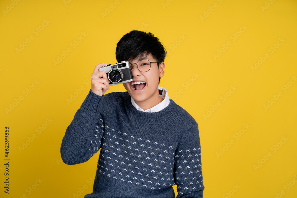 Portrait of a handsome tomboy looking good. Asian woman with short hair on yellow background. She is taking pictures, isolated background. Portrait of a handsome tomboy looking good. Asian woman with short hair on yellow background. She is taking pictures, isolated background.