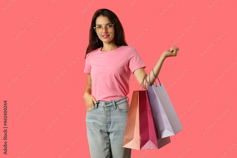 Attractive girl with multicolored paper bags on pink background Attractive girl with multicolored paper bags on pink background