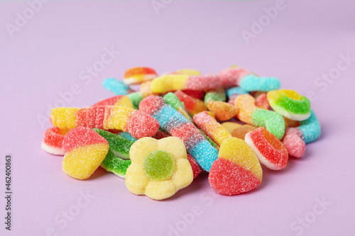 Gummy candies on violet background, close up